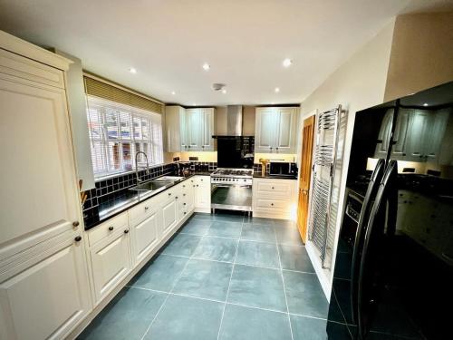 a kitchen with white cabinets and a blue tile floor at Honey Hill Cottage - 4 Bedroom Detached House in Cambridge