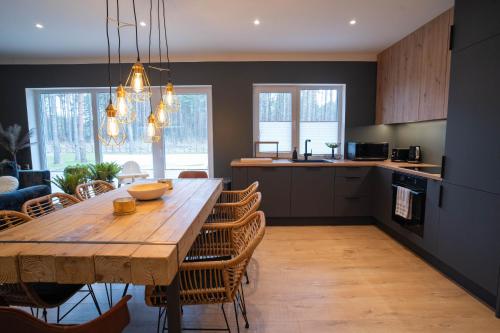 a kitchen and dining room with a wooden table and chairs at Reigi Holiday Home, Hiiumaa with Nordic HotTub & Sauna in Reigi