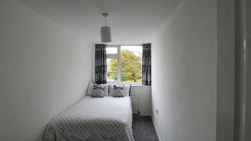 a white bedroom with a bed with a window at Entire House Hertfordshire in Hatfield