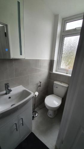 a bathroom with a toilet and a sink and a window at Entire House Hertfordshire in Hatfield
