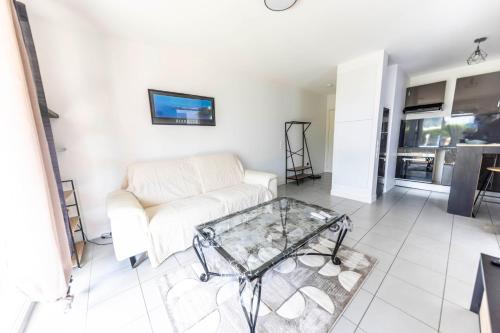 un salon avec un canapé et une table basse en verre dans l'établissement Charmant T2-10 min de la plage, à Saint-Martin-de-Seignanx