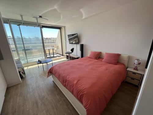 une chambre avec un lit rouge et une grande fenêtre dans l'établissement Studio 4 personnes Cap d'Agde Naturisme CN060-E30, au Cap d'Agde