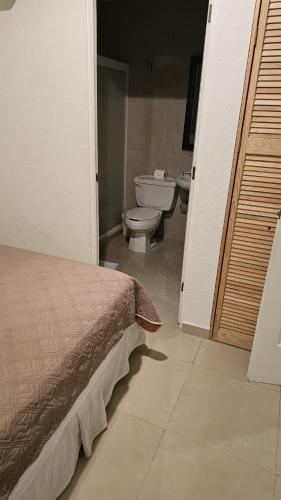 a bedroom with a bed and a toilet in a bathroom at Diamante Lakes Condominium, in front of Arena GNP in Acapulco