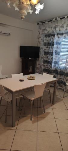 a table and chairs in a living room with a tv at Little Rose garden in Aci Catena
