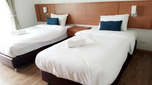 two beds in a hotel room with blue pillows at Donchan Residence in Chiang Mai
