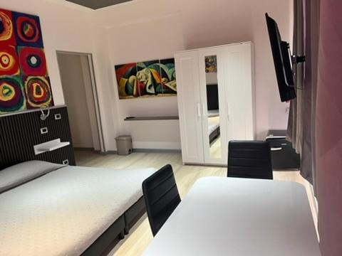 a bedroom with two beds and two chairs and a mirror at Soverato Sweet Home 13 in Soverato Marina