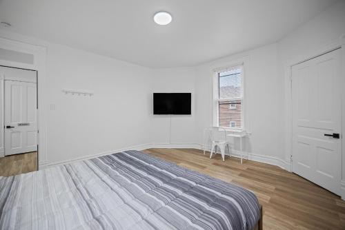 a white bedroom with a bed and a tv on a wall at Shadyside, Pittsburgh !E Modern and Bright Private Bedroom with Shared Bathroom in Pittsburgh