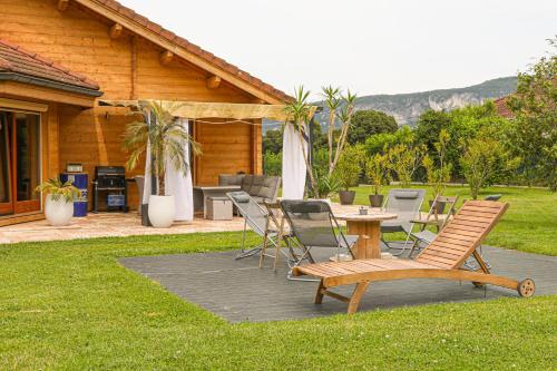 un patio avec une table et des chaises devant une maison dans l'établissement Magnifique Chalet avec piscine et salle de sport, à Peyrieu