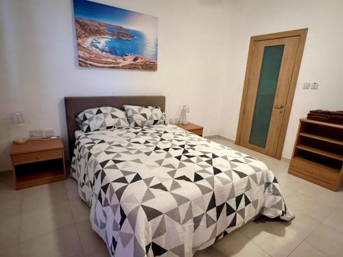 a bedroom with a bed with a black and white comforter at Merhba Apartment in St Paul's Bay