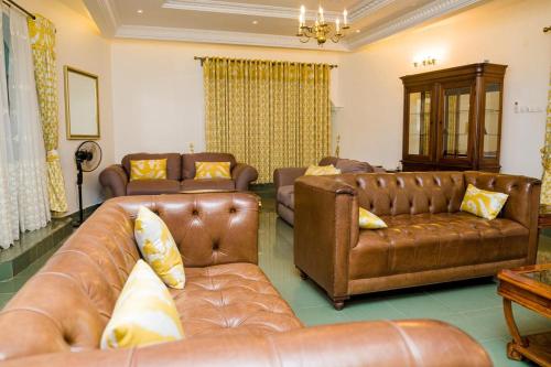 a living room with brown leather couches and chairs at Luxury Villa AC Ensuite Room 8 in Limbe