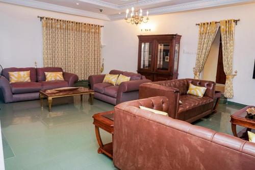 a living room with brown leather couches and a table at Luxury Villa AC Ensuite Room 8 in Limbe