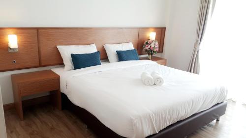 a bedroom with a large white bed with two towels on it at Donchan Residence in Chiang Mai