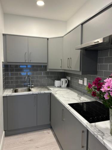 a kitchen with white cabinets and a sink and flowers at KCM Urban Retreats in Cobh