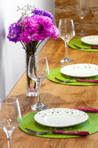 a wooden table with plates and glasses and purple flowers at 5- Luxury suite for 4 in the most central part of Rhodes! in Rhodes Town