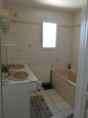 La salle de bains est pourvue de 2 lavabos, d'une baignoire et d'une fenêtre. dans l'établissement Maison avec piscine privée à Siorac en Périgord, à Siorac-en-Périgord
