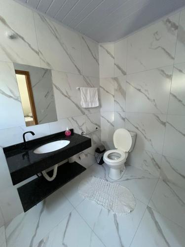 a white bathroom with a sink and a toilet at Pousada casa da amizade in Penha