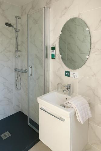 une salle de bain blanche avec un lavabo et une douche dans l'établissement Logis Hôtel du Cirque Troyes centre historique, à Troyes