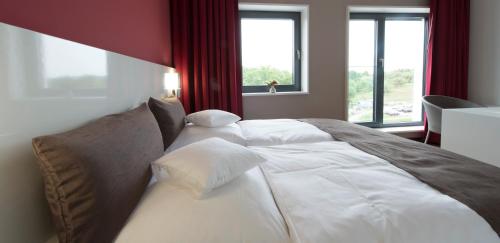 a large white bed in a room with windows at GZT Das Gästehaus in Tübingen