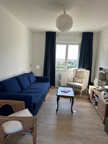 un salon avec un canapé bleu et une chaise dans l'établissement Maison face à la mer, à Saint-Marcouf