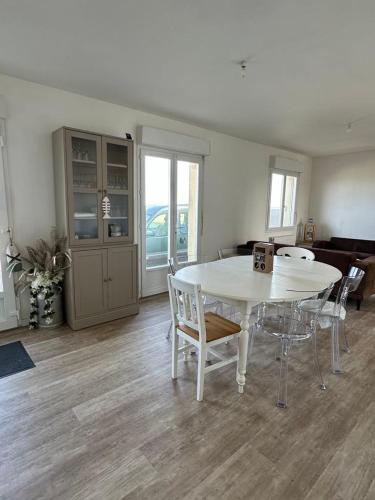 une salle à manger avec une table et des chaises blanches dans l'établissement Maison face à la mer, à Saint-Marcouf
