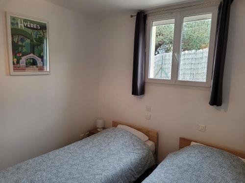 une chambre avec deux lits et une fenêtre dans l'établissement Giens-T2 charme-7m à pied plage - Rez de jardin, à Hyères