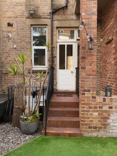 a brick house with a white door and stairs at Verulam Palms - Private Garden & Parking in Bournemouth
