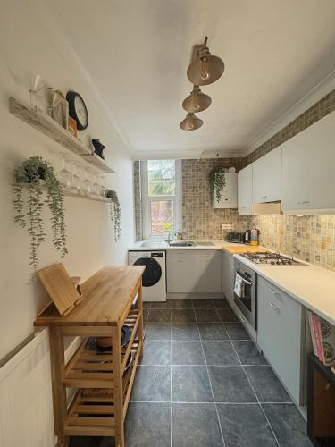 a kitchen with white cabinets and a wooden table at Verulam Palms - Private Garden & Parking in Bournemouth