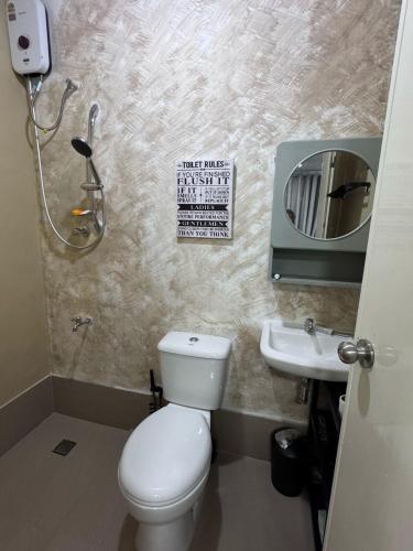 a bathroom with a toilet and a sink and a mirror at Cozy Rustic Corner House Subic in Subic