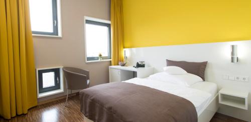 a bedroom with a bed and a yellow wall at GZT Das Gästehaus in Tübingen