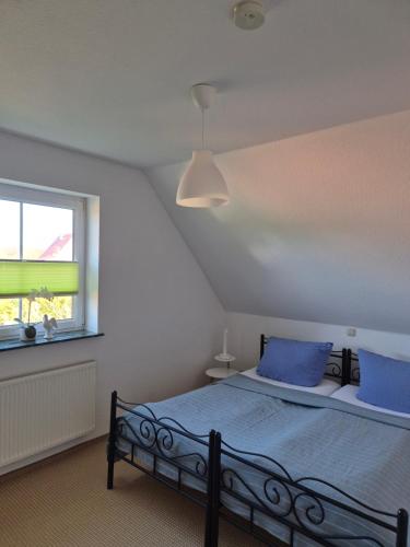 a bedroom with a bed with blue pillows and a window at FeWo 3 im Haus Lohme OT Hagen in Hagen