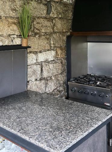 Il comprend une cuisine avec une cuisinière et un mur en pierre. dans l'établissement Chambre cosy à 5 min de la plage, à Viagenti