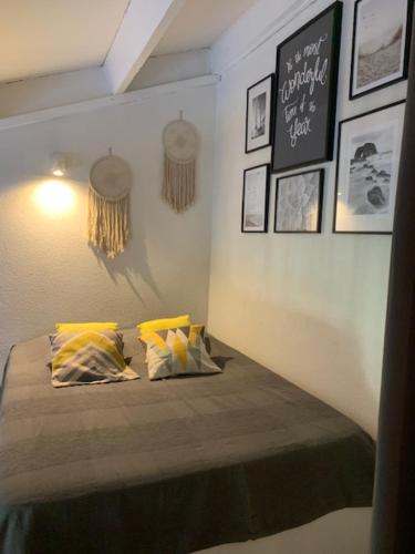 une chambre avec un lit avec des oreillers jaunes dessus dans l'établissement Cosy T1 avec mezzanine, à 7' à pied de la plage et du centre, wifi, clim, parking privé, piscines, à Canet