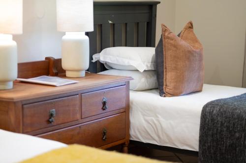 a bed with a pillow on top of it with a night stand at Aan d'Oewer in Citrusdal