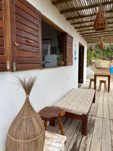 a porch with a table and a bench and a window at Chalé Green Vila Mathilde in Icapuí
