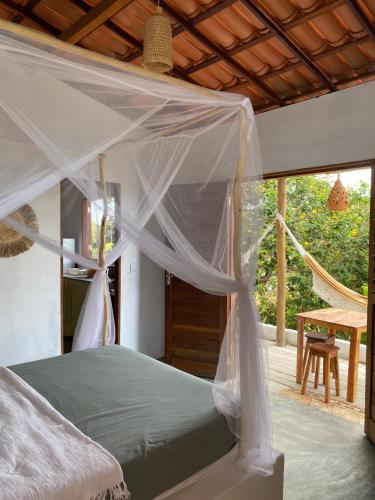 a bedroom with a canopy bed and a patio at Chalé Green Vila Mathilde in Icapuí