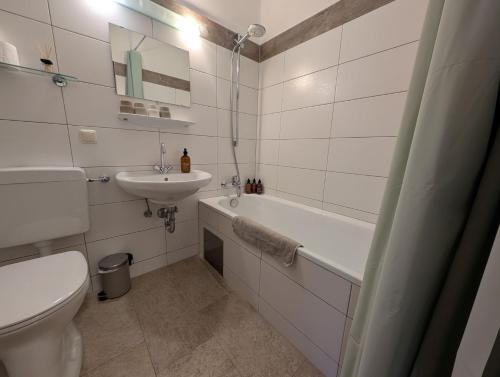 a bathroom with a sink and a tub and a toilet at Ferienwohnung Jogginghose in Bad Goisern