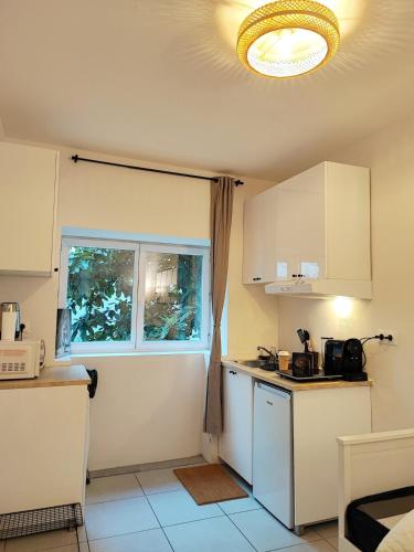 une cuisine avec des armoires blanches et une fenêtre dans l'établissement Cosy studio 14m2 centre-ville, à Villeurbanne