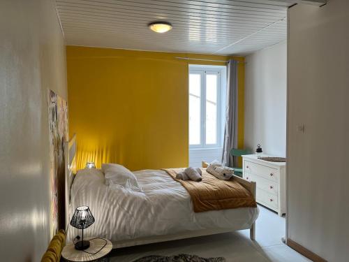 une chambre avec un lit avec un mur jaune dans l'établissement Logis en Périgord - Entre bastides et vignobles - 2 personnes, à Saint-Aubin-de-Lanquais