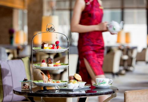 a woman standing behind a table with a tray of food at Midtown Shangri-La, Hangzhou - around 5 minutes walking distance to West Lake in Hangzhou