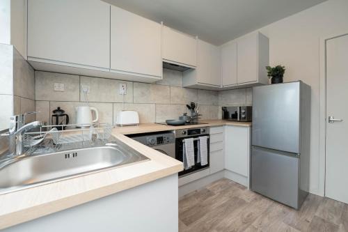 a kitchen with white cabinets and a stainless steel refrigerator at #34 Two bed apt Private Parking Stylish & homely - Near Tamworth Castle - Sleeps 5 -"Perfect for Contractors and Families" - Free Parking in Fazeley