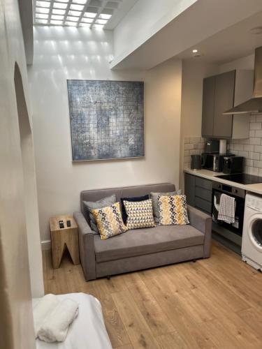 a living room with a couch and a kitchen at Gorgeous little gem in London