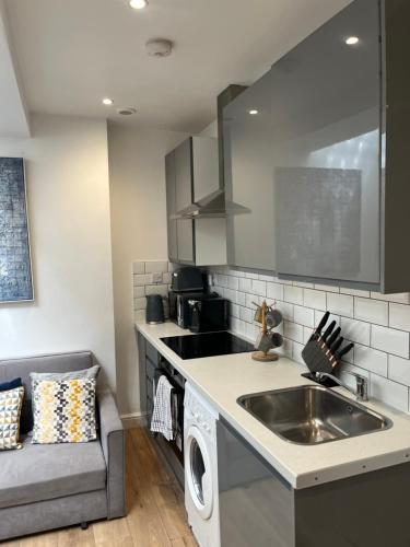 a kitchen with a sink and a couch in it at Gorgeous little gem in London
