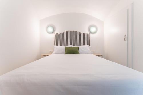 a bedroom with a large white bed with a green pillow at Apartamentos Turísticos Zibá in Merida