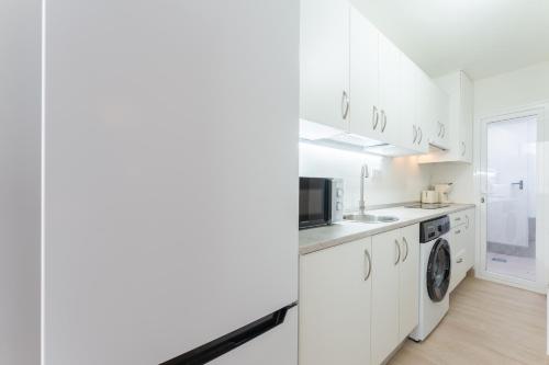 a kitchen with white cabinets and a washer and dryer at Apartamentos Turísticos Zibá in Merida