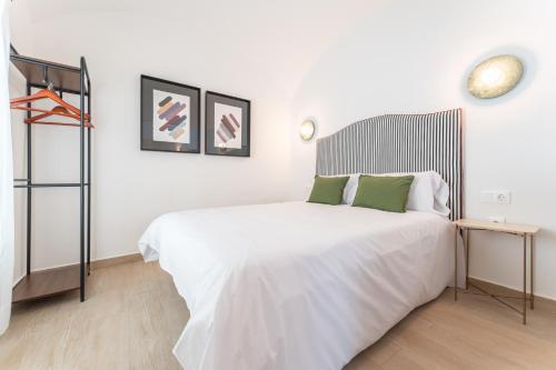 a bedroom with a large white bed with green pillows at Apartamentos Turísticos Zibá in Merida