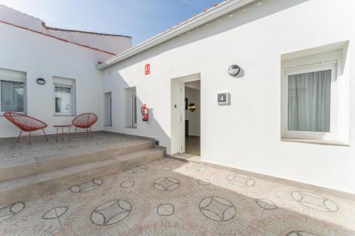 a house with two red chairs on a patio at Apartamentos Turísticos Zibá in Merida