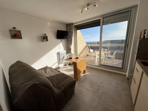un salon avec un canapé et une grande fenêtre dans l'établissement Studio 2 couchages CAP D'AGDE NATURISME CN060-L10, au Cap d'Agde