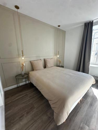un grand lit blanc dans une chambre avec une fenêtre dans l'établissement Les Jasmins - Centre Ville de Saumur, à Saumur