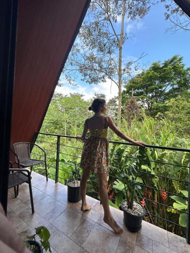 a woman in a dress standing on a balcony at Yarumo Lodge, Río Celeste Black Chalets in Bijagua