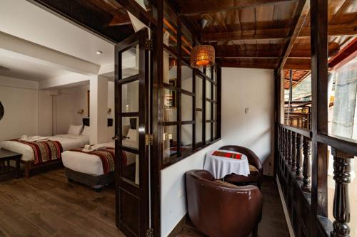 a room with a bedroom with two beds and a couch at Gringo Bill's Boutique Hotel in Machu Picchu